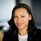 Headshot of a woman in her 30s who has heritage from Poland with light-medium skin tone and black shoulder length curled hair. She is wearing a black blazer, white shirt and she is looking at the camera. 