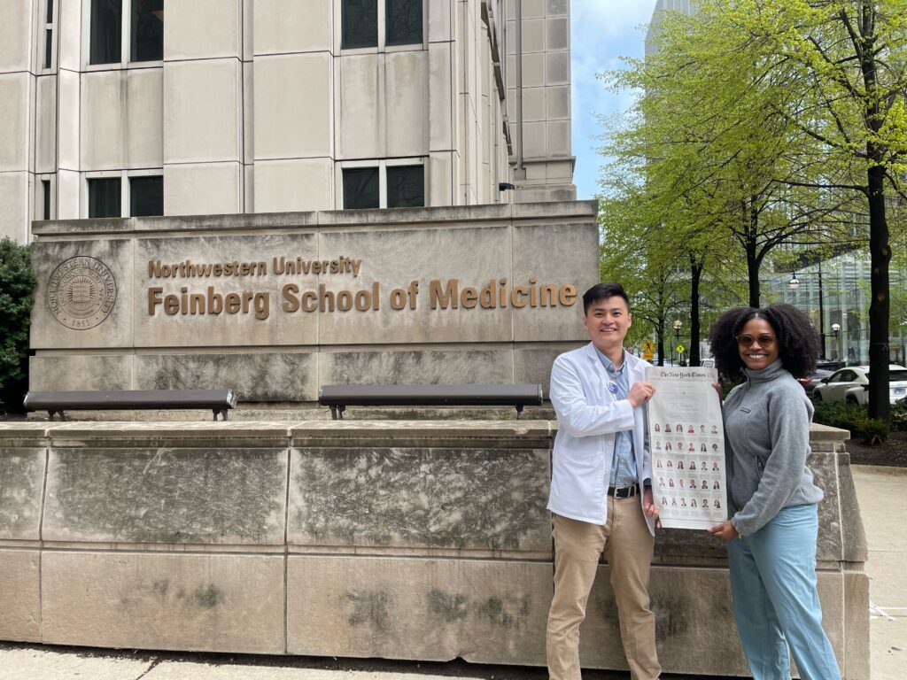 Photograph of a man in his 20s who has heritage from China with light skin tone and short black hair. He is standing in front of a stone building "School of Medicine" can be seen in brass lettering. 