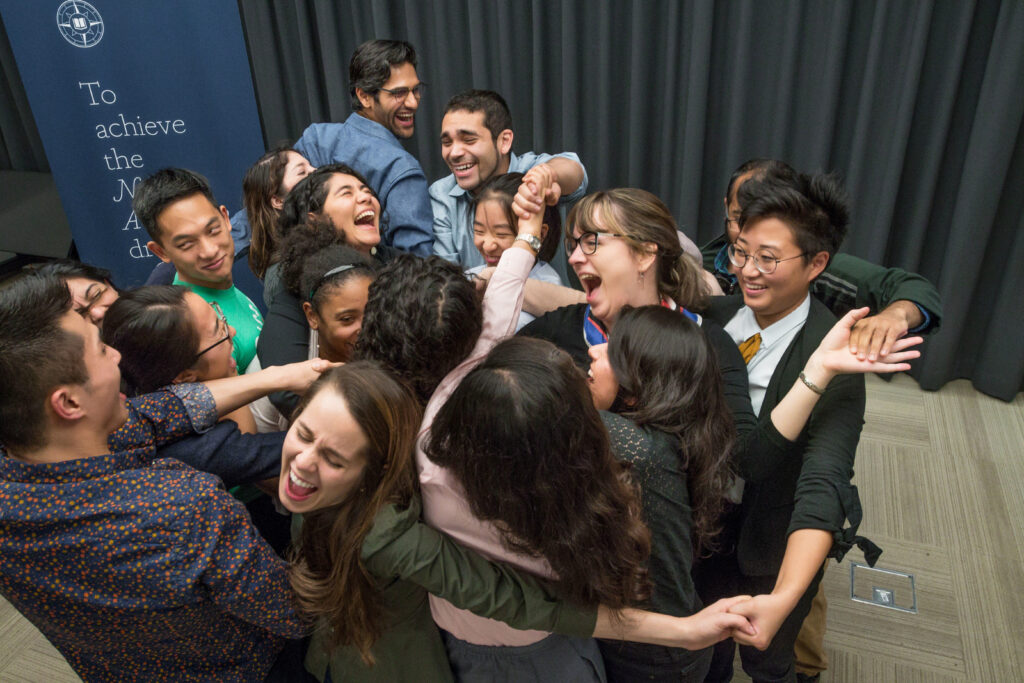 Photograph of a group of people looking excited and in a group hug.