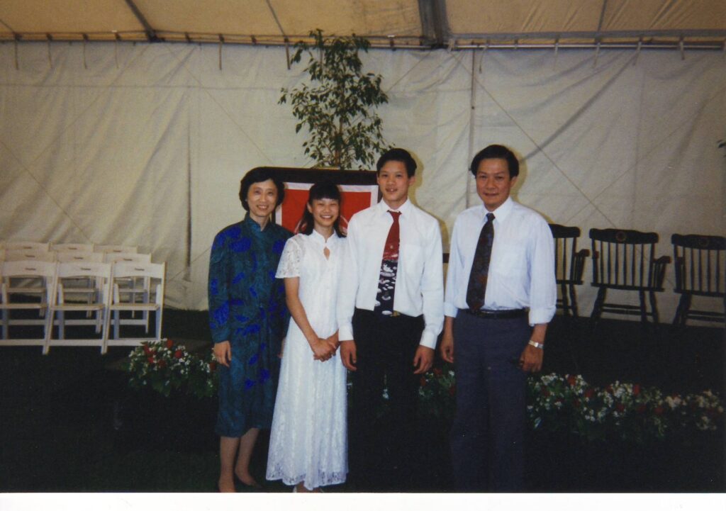 Old photograph of four people. The woman on the left is wearing a blue and green patterned dress, the two men have on slacks, white button up shirts and ties. 