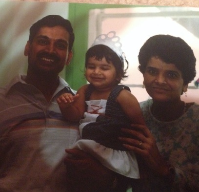 Old photograph of a family, dad, mom and toddler. The family has heritage in India with medium skin tone and black hair. 