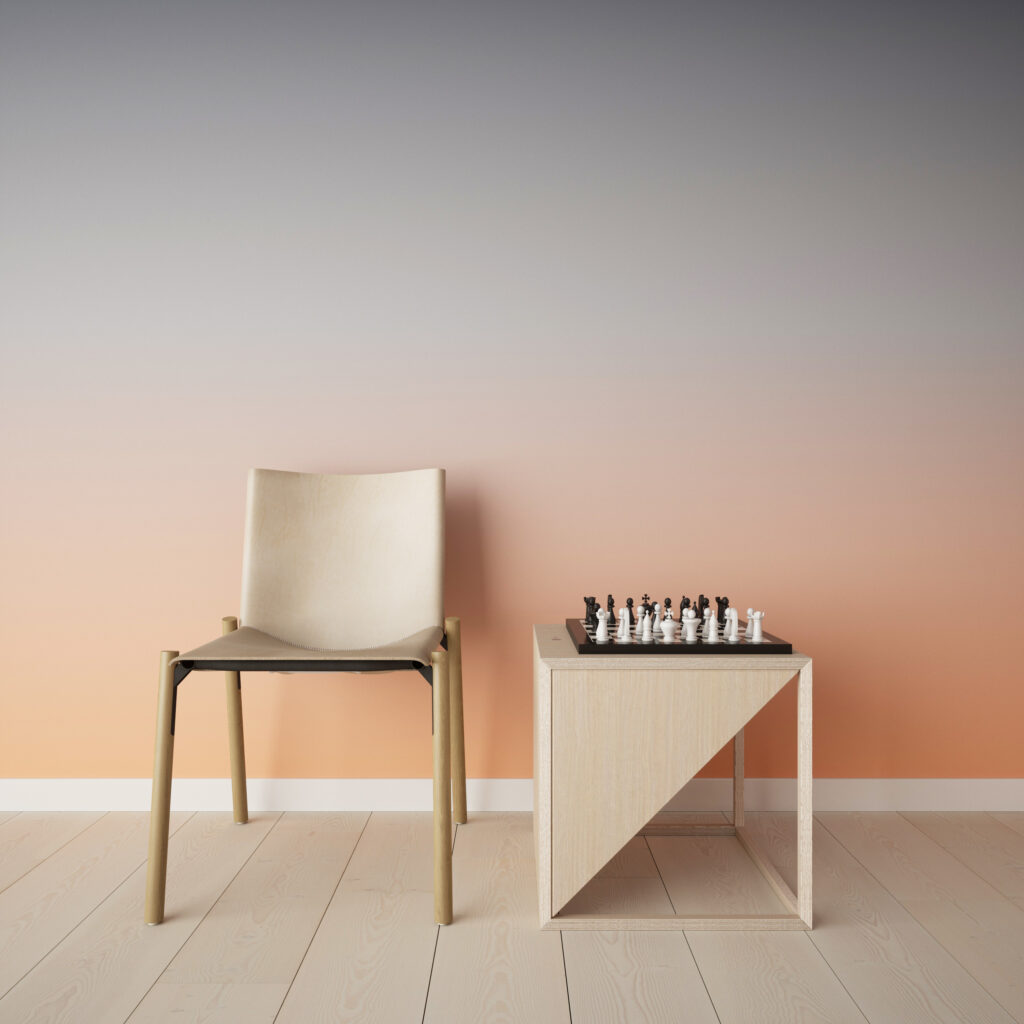 Photograph of an off-white chair next to the off-white speaker, it's facing the right so we see the angle cutting the cube in half. There is a chess board on top of the speaker. The wall behind these things is an orange to grey ombre. 