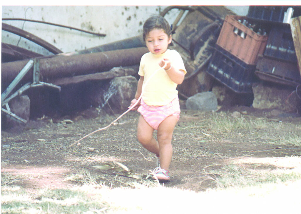 A young child walks, holding a stick.