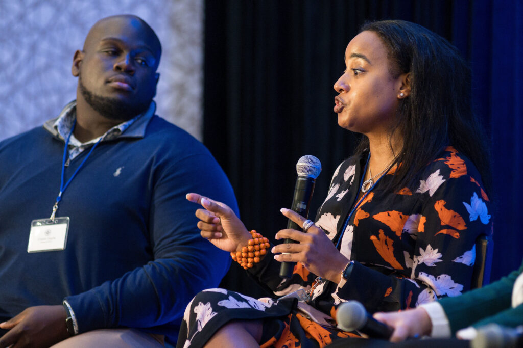 Photograph of two people, the one on the left is a man in his 20s, on the right is a woman in her 40s - she is talking.