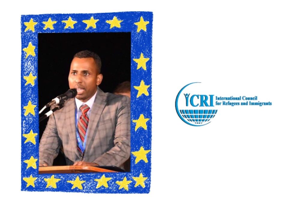 Blue crayon style frame with yellow stars: inside is a photo of a man wearing a grey suit and speaking at a microphone not looking at the camera; Logo: "International Council for Refugees and Immigrants" in light blue font with a circle containing YCRI in the center.