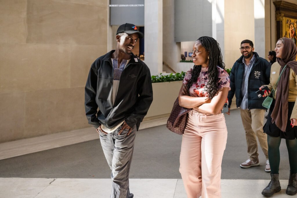 Photograph of two people walking and talking, on the left a man in his 20s and on the right a woman in her 20s.