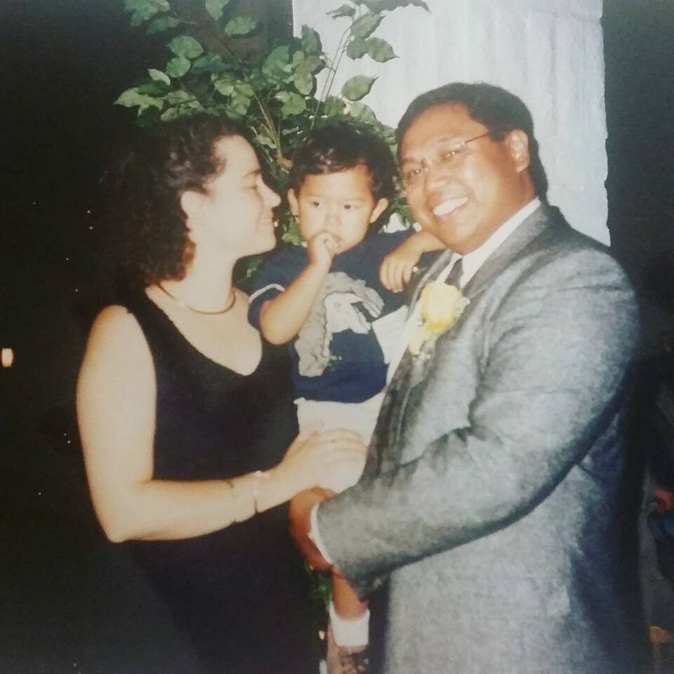 Old photograph of two people holding a child, they are all dressed up and look happy.