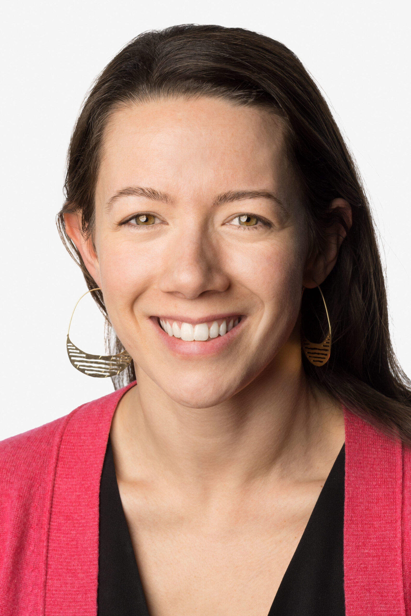 Headshot of a woman in her 30s with light skin tone and dark brown long straight hair. She is wearing dangly earrings and smiling at the camera.