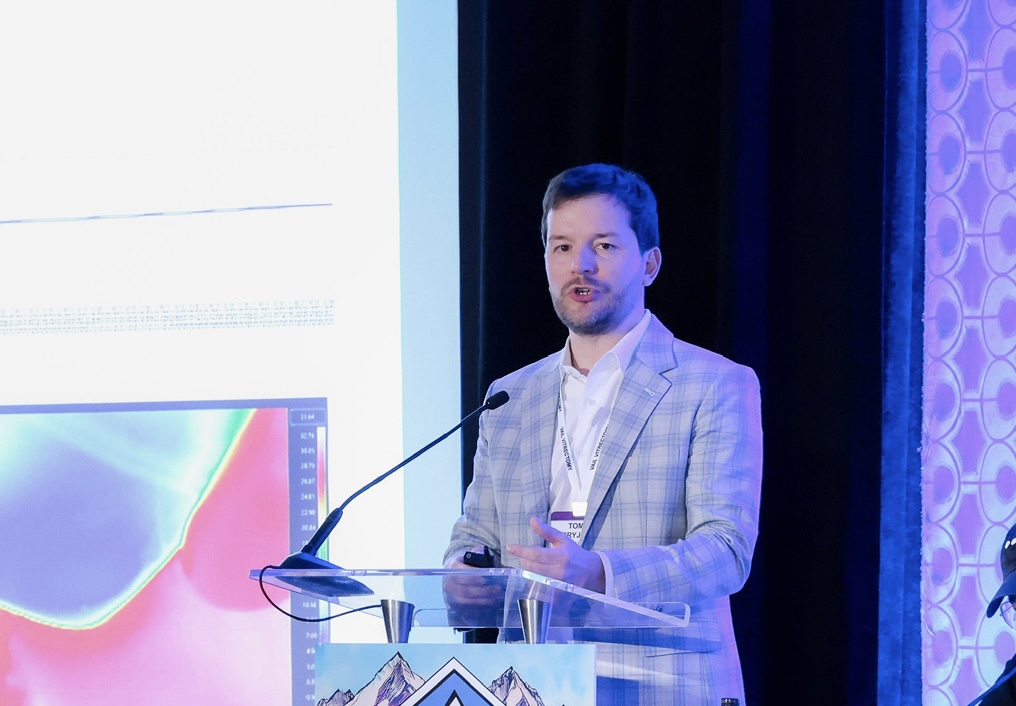 Tomasz P. Stryjewski, MD Chief Scientific Officer & Co-Founder Pykus Therapeutics, Inc. - Tommy stands at a lectern, delivering a speech and bathed in blue light.